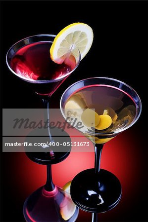 Classical martini in glass on reflection surface, garnished  olive and lemon.