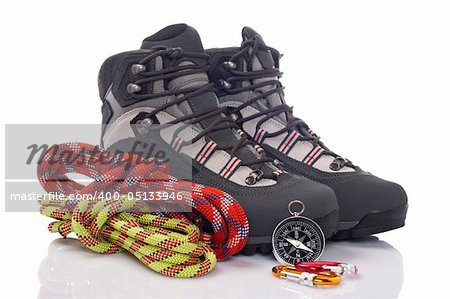 Hiking boots, two rope and compass reflected on white background