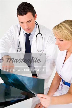 A male doctor examining an X-ray with his female nursing colleague