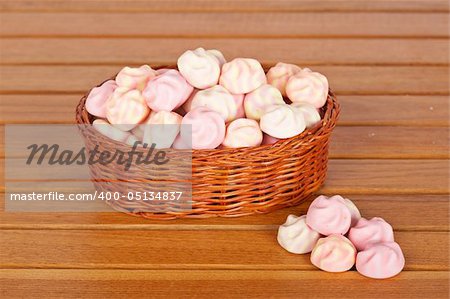 Pink marshmallows in the basket on wooden background