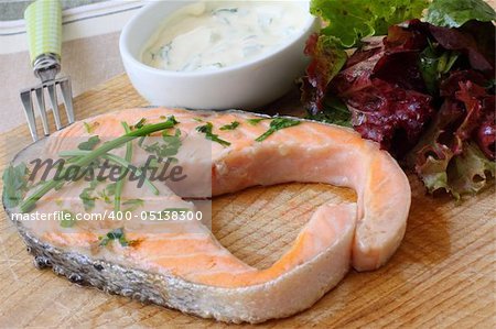 grilled salmon steak on wooden board with salad