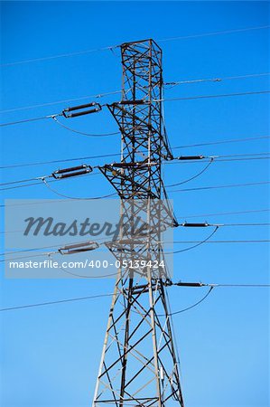 High tension electric pole against blue cloudless sky
