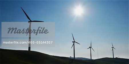 Four wind turbines silhouettes on top of hill