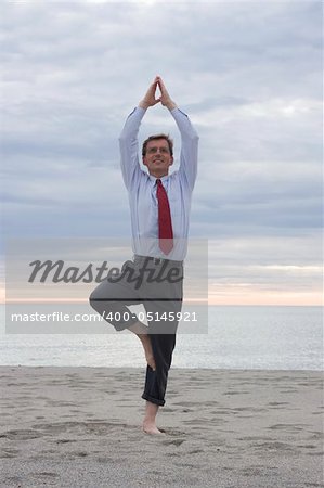 Businessman doing yoga on a beach