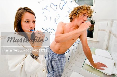 A couple brushing their teeth together in a bathroom