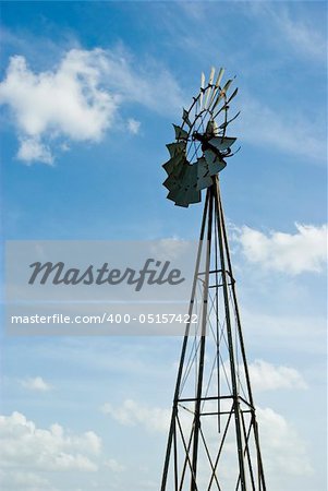 an old windmill against a bright blue sky with scattered clouds