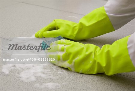 Hand in glove scrubbing tile with a sponge
