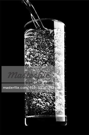 Sparkling water being poured into a glass against a black background