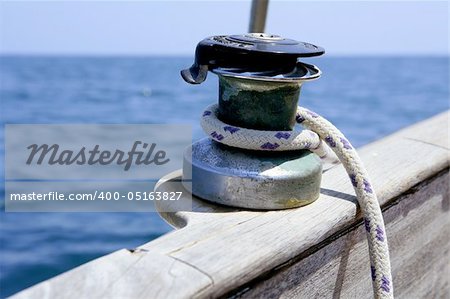 Sail boat winch with marine rope arround. Wooden sailboat