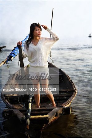 Lady looking at sunrise on traditional fisherman boat, the area was covering by fog/mist