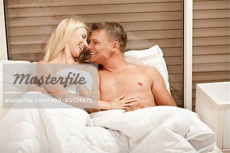 Caucasian couple embracing and enjioying in bed