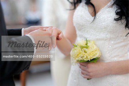 Groom is putting the ring on bride's finger