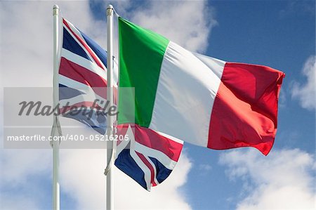 Italian and british flags on a pole moved by wind