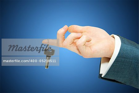 hand holds a key isolated on blue