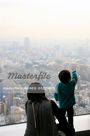 A little japanese boy is showing something to his mother in the immensity of the city of tokyo. The scene is taking place in the roppongi hill skyscraper .