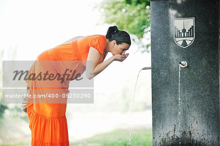 beautiful young happy pregnant woman outdoor in bright nature in orange dress