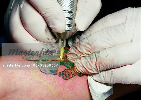 A tattoo artist applying his craft onto the hand of a female