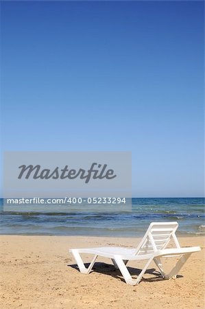 one deckchairs on the beach under blue sky