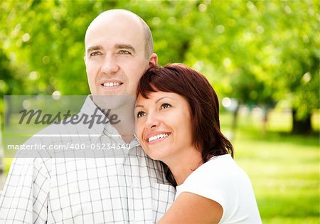 adult couple of husband and wife in park, both smiling and looking away from camera