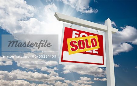 Sold For Sale Real Estate Sign over Clouds and Blue Sky with Sun Rays.