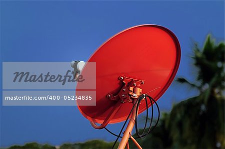 A red satellite dish against the blue sky background