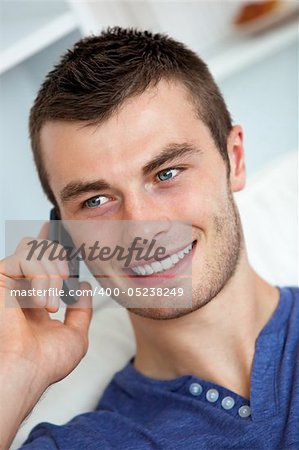 Handsome young man talking on phone in living room