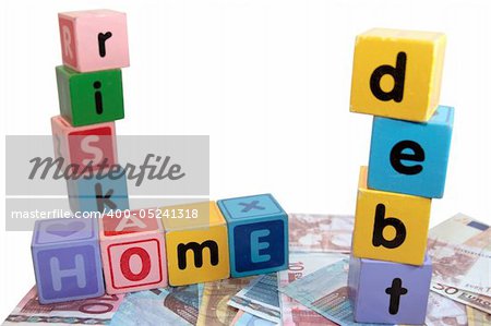 assorted childrens toy letter building blocks against a white background on money that spell home debt risk