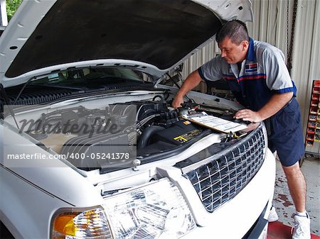 Auto mechanic performing a routine service inspection in a service garage.