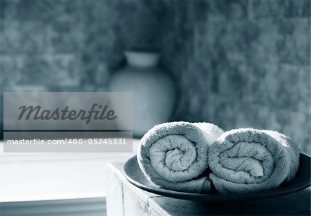 Two white rolled towels in a bathing room