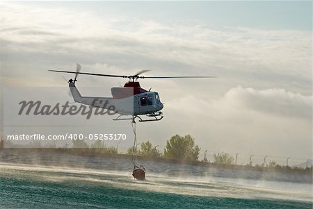 Fire brigade helicopter dipping the water container to refill