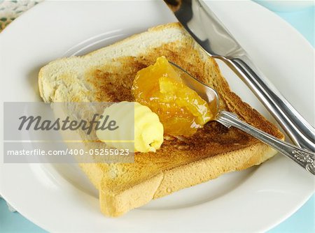 Dollops of orange marmalade and butter on a slice of toast.