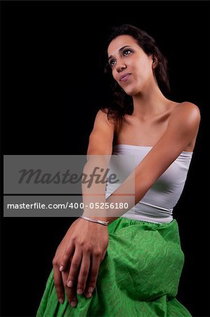 young and beautiful woman  seated and pensive, isolated on black background