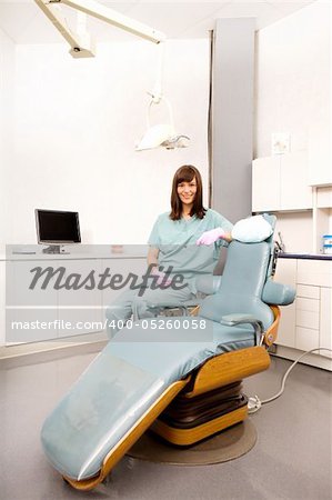 A dental hygienist sitting at a dental chair in a clinic