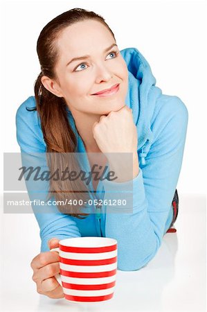 A beautiful young healthy woman lying down with a cup of tea or coffee smiling.