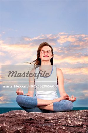 Portrait of young teenage girl practicing yoga at sunset