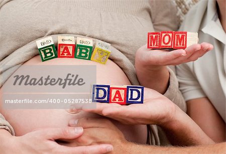 Close up of future parents holding cubes forming the words mom ,dad and baby
