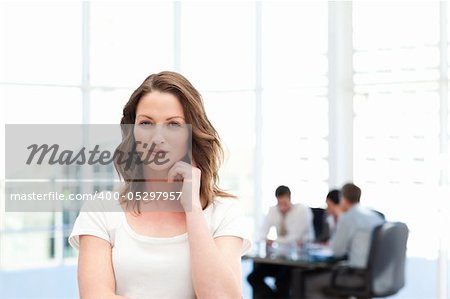 Pensive businesswoman standing in front of her team while working in the background