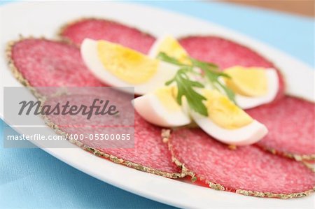 Salami with pepper crust and eggs on a plate. Shallow dof