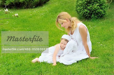 Young mother and daughter resting in meadow