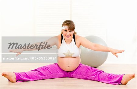 Smiling beautiful pregnant woman doing stretching exercises