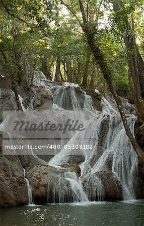 Waterfall in jungle in Thailand, sunshine entrenches through foliage