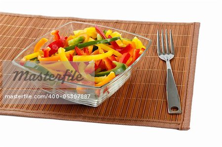 Mix of fresh vegetables from a color paprika in a glass plate on a white background with a plug