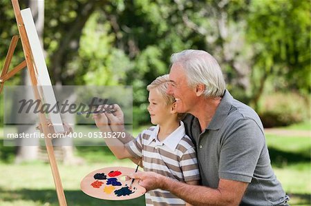 Happy Grandfather and his grandson painting in the garden