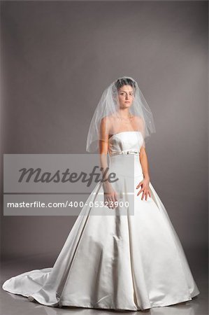 beautiful bride is standing in wedding dress on grey background