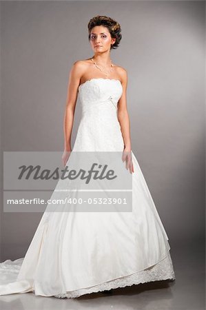 beautiful bride is standing in wedding dress on grey background