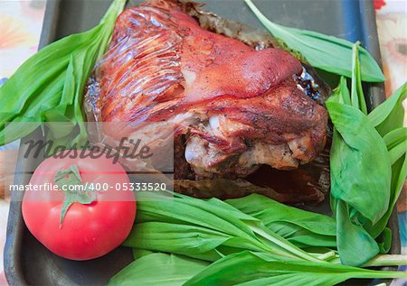Baked with spices a gammon of a foot with a tomato and leaves of green salad