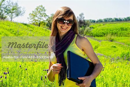 Smiling beautiful woman with laptop outdoor. Sunny summer day.