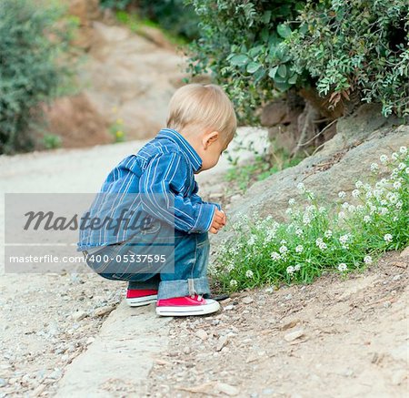 Cute 2 years old boy sitting on the footpath in the park