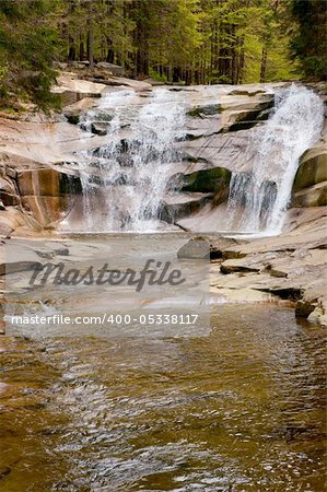 Cascading waterfall over natural rocks in forest