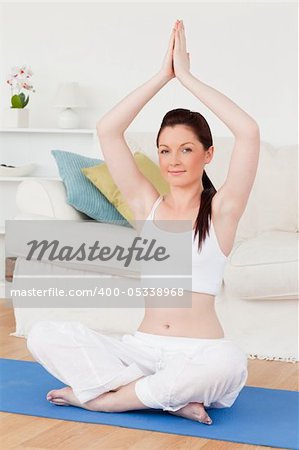 Pretty female doing yoga on a gym carpet in the living room